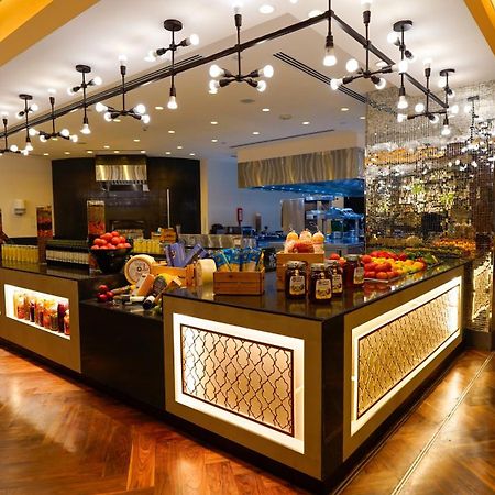 מלון מכה Jabal Omar Hyatt Regency Makkah מראה חיצוני תמונה The photo shows a stylish and modern buffet area in a restaurant or hotel. The design features a sleek counter with various food items displayed, including fresh fruits. The space is well-lit with pendant lights hanging from the ceiling, creating a w