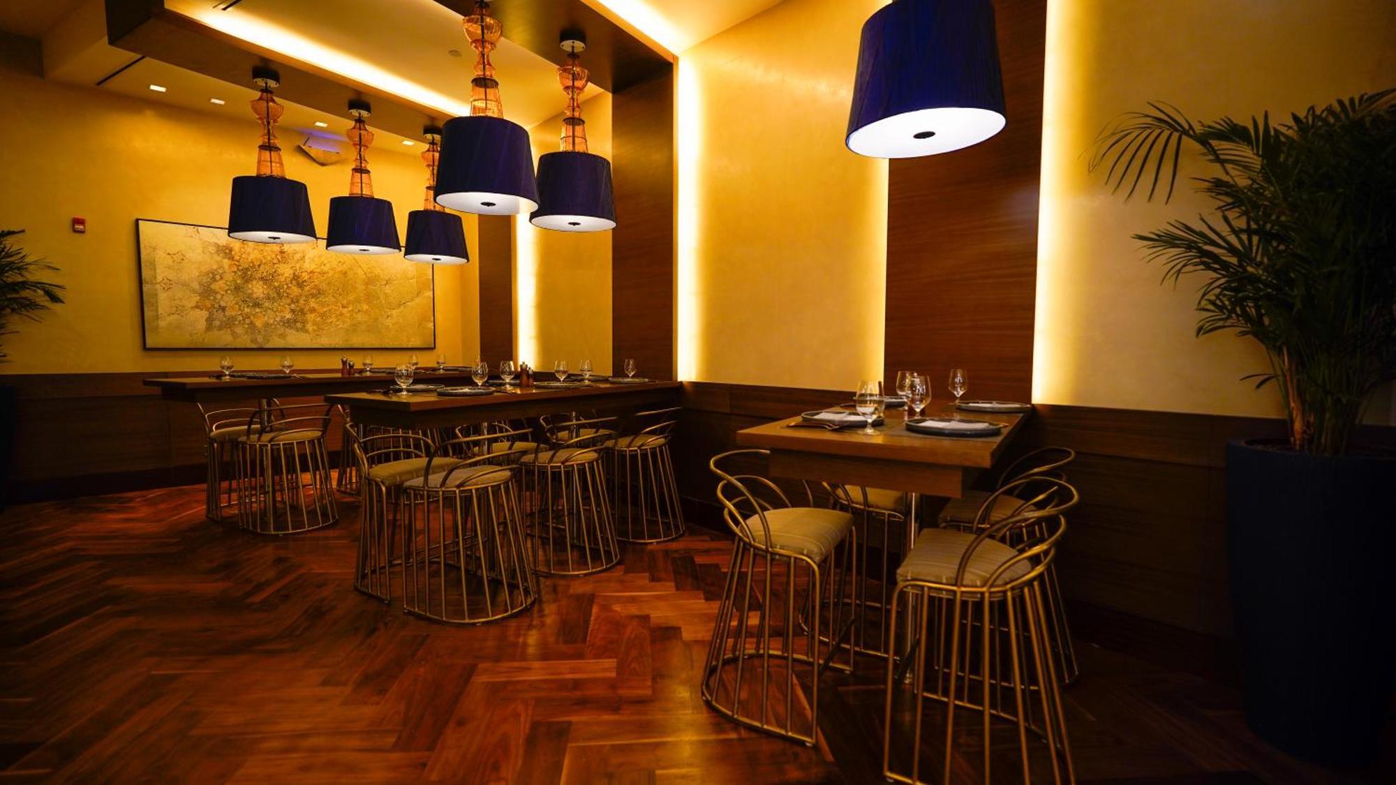 מלון מכה Jabal Omar Hyatt Regency Makkah מראה חיצוני תמונה The photo shows an elegantly designed restaurant interior. It features stylish seating arrangements with gold wire chairs paired with tables. The ambient lighting is warm, with a mix of recessed lights and pendant lamps that have blue shades, creatin