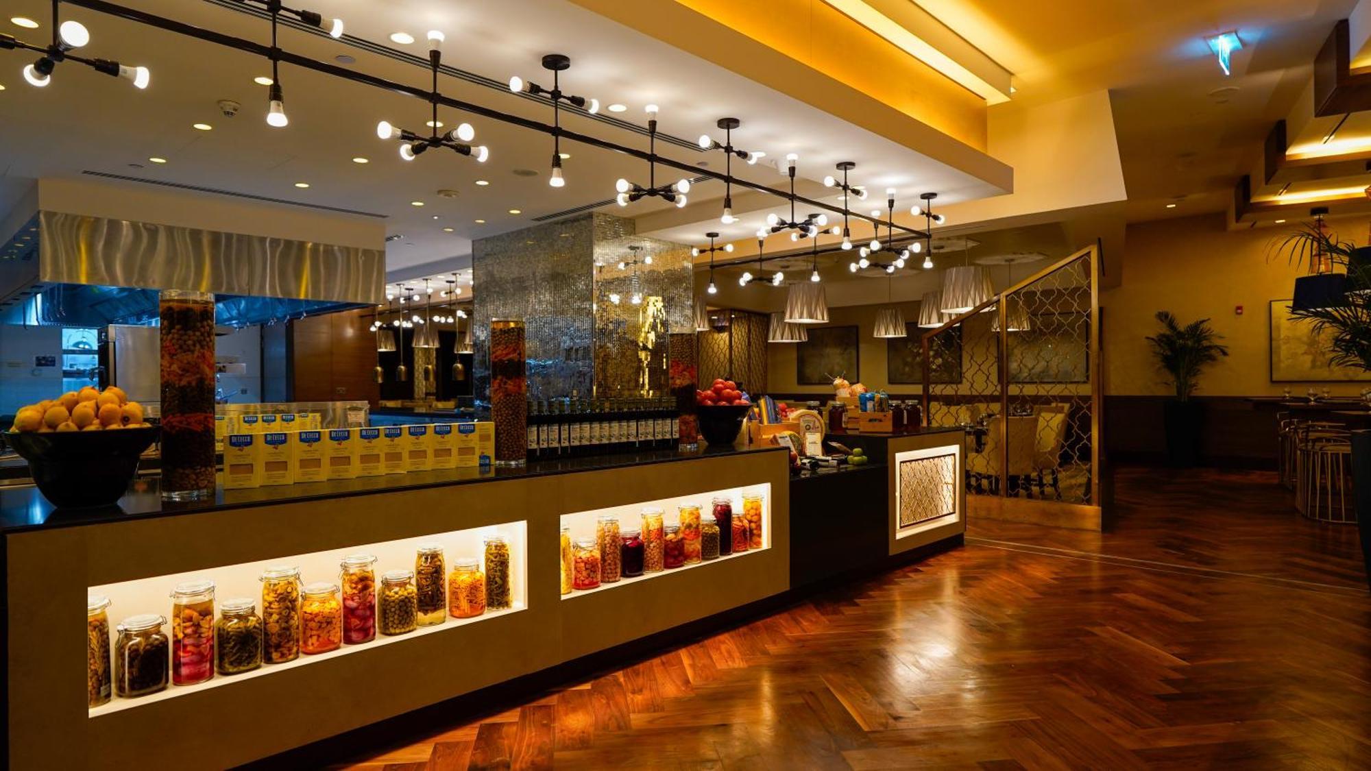 מלון מכה Jabal Omar Hyatt Regency Makkah מראה חיצוני תמונה The photo shows a stylish interior of a restaurant or café. It features a well-lit space with modern lighting fixtures hanging from the ceiling. The focal point is a counter area with jars filled with colorful ingredients or snacks, illuminated by li