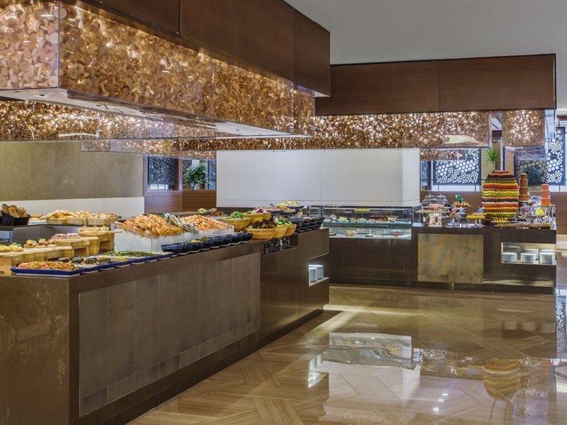 מלון מכה Jabal Omar Hyatt Regency Makkah מראה חיצוני תמונה The photo shows a stylish buffet area, likely in a restaurant or hotel. There are several food displays arranged on long tables with shiny surfaces. The buffet features a variety of items, which may include pastries, bread, and other dishes. The area