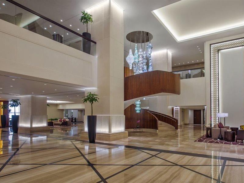 מלון מכה Jabal Omar Hyatt Regency Makkah מראה חיצוני תמונה The image shows a spacious and modern hotel lobby. It features elegant interior design with high ceilings and polished marble floors. A prominent wooden staircase with a stylish design is located in the center, leading to an upper level. There are de