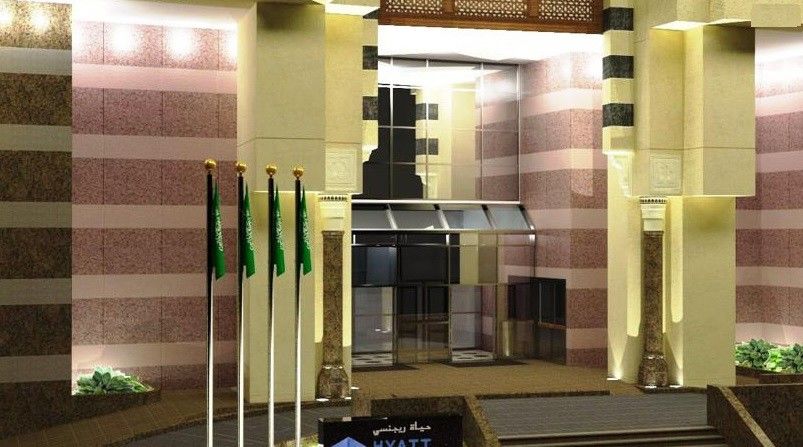 מלון מכה Jabal Omar Hyatt Regency Makkah מראה חיצוני תמונה The photo shows a building entrance decorated in a luxurious style. It features a prominent glass entrance with a modern design. In front of the entrance, there are several vertical flags, which appear to represent Saudi Arabia. The architecture incl