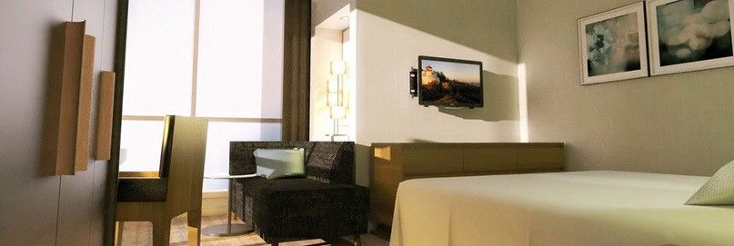 מלון מכה Jabal Omar Hyatt Regency Makkah מראה חיצוני תמונה The photo shows a modern hotel room or living space featuring a small seating area. On the left, there is a dark-colored couch and a glass side table. Across from the couch, mounted on the wall, is a flat-screen television. The room has light-colored