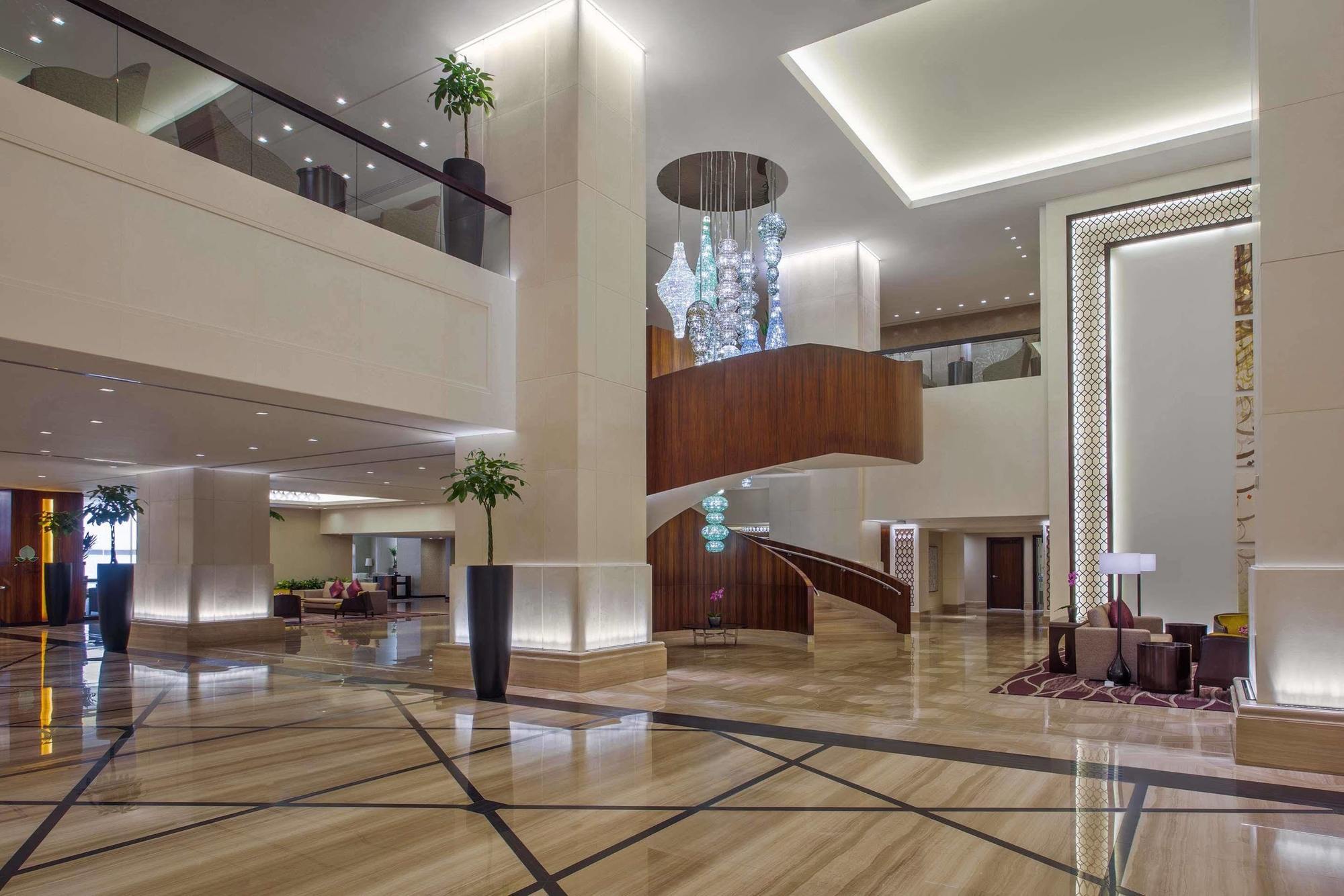 מלון מכה Jabal Omar Hyatt Regency Makkah מראה חיצוני תמונה The photo shows a spacious and elegantly designed hotel lobby. The interior features large marble flooring with a geometric pattern, complemented by modern lighting fixtures. A grand staircase with wooden accents is prominent in the center, leading t
