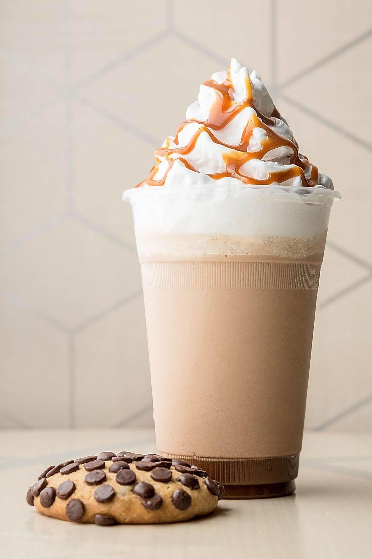 מלון מכה Jabal Omar Hyatt Regency Makkah מראה חיצוני תמונה The photo shows a tall cup of a creamy beverage, likely a milkshake or a blended coffee drink. The drink has a light brown color with a frothy top, which is topped with whipped cream. Drizzled over the whipped cream is a thick caramel sauce, adding a