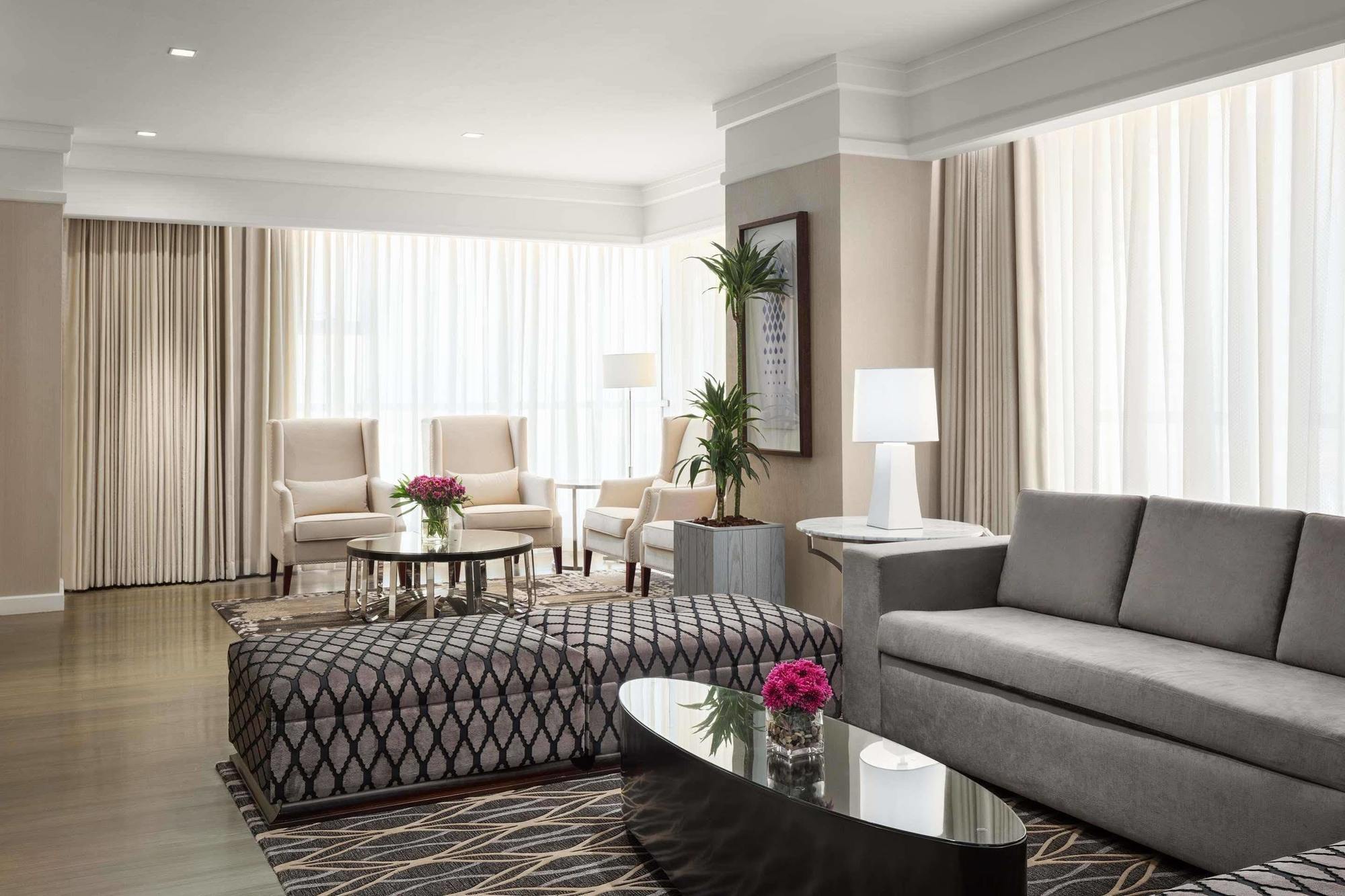 מלון מכה Jabal Omar Hyatt Regency Makkah מראה חיצוני תמונה The photo depicts a modern living room with a stylish and inviting design. There are large windows covered with light-colored curtains that allow natural light to fill the space. The furniture includes a gray sofa, a patterned ottoman with a geometri