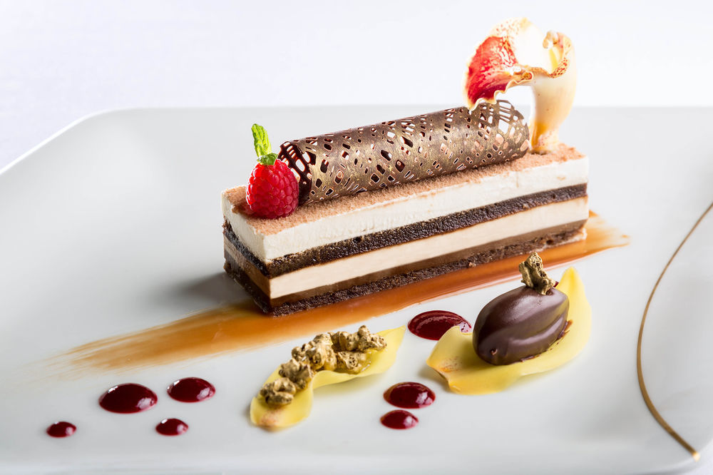 מלון מכה Jabal Omar Hyatt Regency Makkah מראה חיצוני תמונה The photo showcases an elegantly plated dessert. It features a layered cake with different textures and flavors, including chocolate and cream layers. The dessert is topped with a decorative chocolate tube and garnished with fresh raspberries and a s