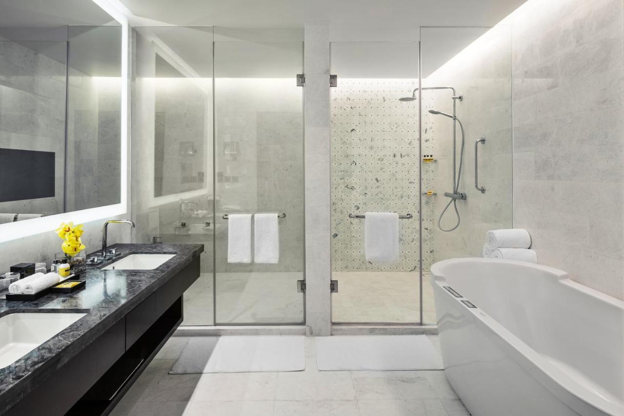 מלון מכה Jabal Omar Hyatt Regency Makkah מראה חיצוני תמונה The photo shows a modern bathroom with a sleek design. It features a glass shower enclosure with a rainfall showerhead and a stylish bathtub. The floor and walls have a light-colored stone or tile finish, giving a clean and minimalist look. There's a