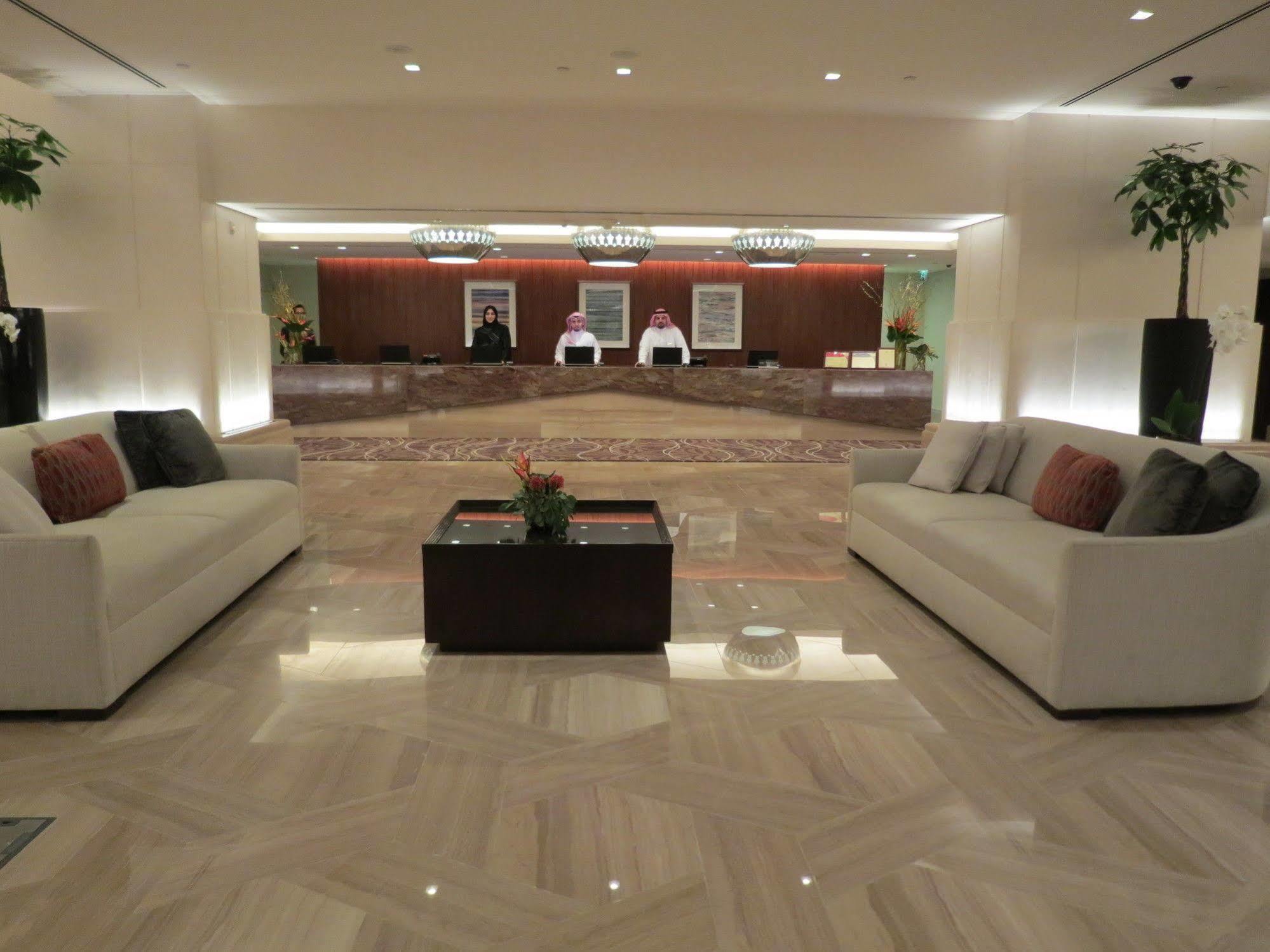 מלון מכה Jabal Omar Hyatt Regency Makkah מראה חיצוני תמונה The photo shows a modern hotel lobby. In the foreground, there are two light-colored sofas with decorative pillows, positioned facing each other. A small coffee table with a plant sits between the sofas. 

In the background, there is a reception desk