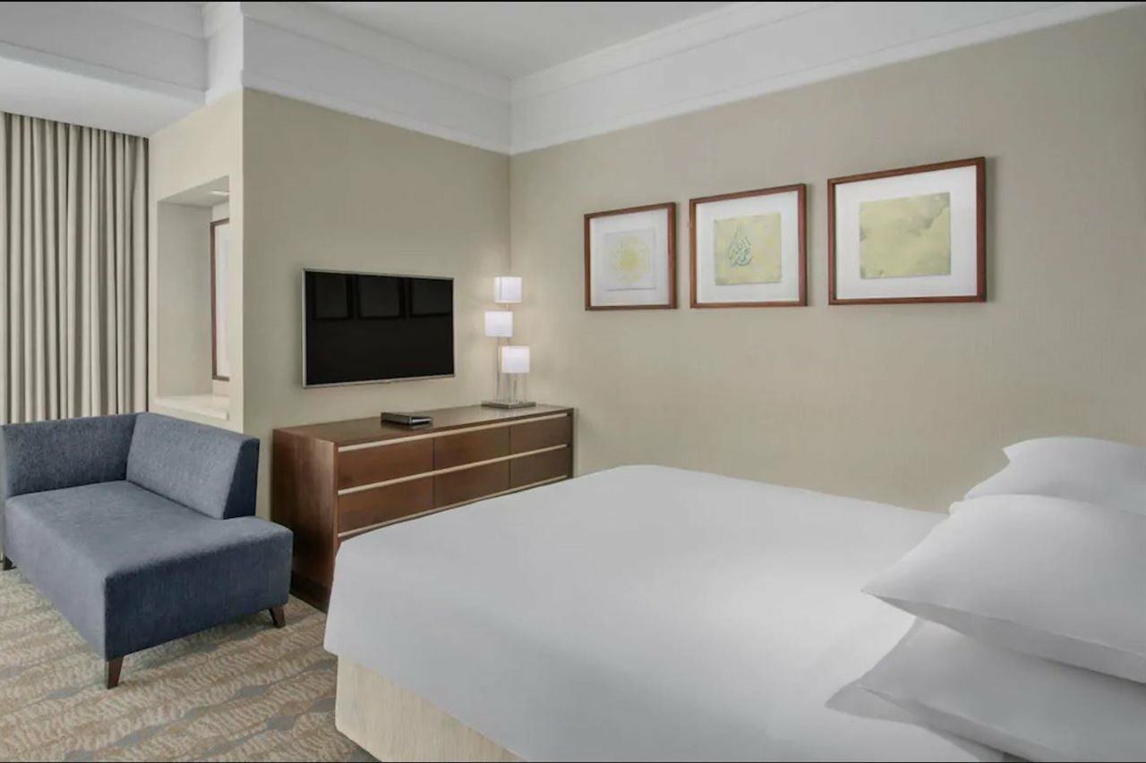 מלון מכה Jabal Omar Hyatt Regency Makkah מראה חיצוני תמונה The photo shows a modern hotel room. It features a neatly made bed with white linens and multiple pillows. On the wall opposite the bed, there is a flat-screen television mounted, along with a modern wooden dresser. Above the dresser, three framed ar